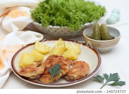 Quail schnitzels from legs on the plate and boiled potatoes with pickles.  140724737