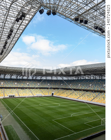 Modern soccer stadium with empty stands and lush green field in Lviv oblast Ukraina under a bright blue sky 140724825