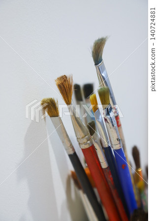 Collection of artist paintbrushes in various sizes arranged against a wall within a creative workspace showing the tools of artistic expression 140724881