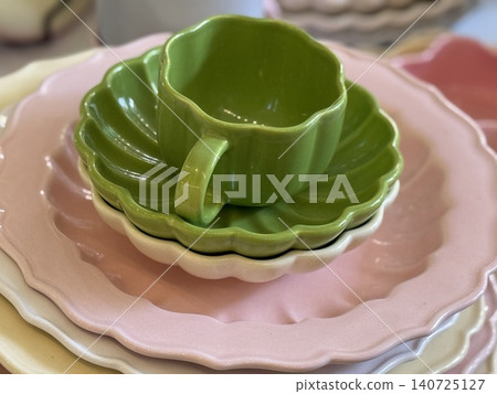 Ceramic dishware set featuring an array of colorful stacked plates and a green cup Ceramic dishware set featuring an array of colorful stacked plates and a green cup 140725127