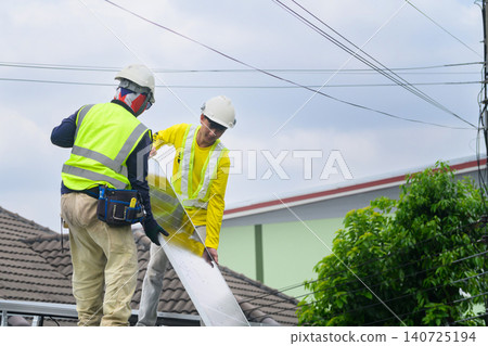 Two Technicians Installing Solar Panel on Residential Rooftop in Safety Gear Two Technicians Installing Solar Panel on Residential Rooftop in Safety Gear 140725194