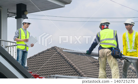 Construction Workers Installing Solar Panel on Residential Rooftop with Engineer Supervising Construction Workers Installing Solar Panel on Residential Rooftop with Engineer Supervising 140725270