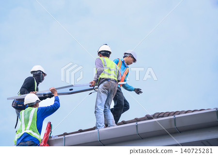 Workers Installing Solar Panels on Residential Rooftop Team Carrying Photovoltaic Modules During Installation 140725281