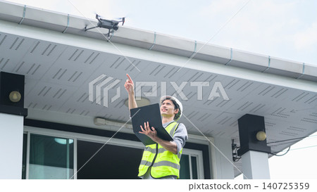 Engineer in Safety Vest Using Drone to Inspect Building Roof While Holding Laptop Outdoors 140725359