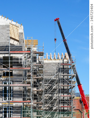 Multi Storey Building Construction Site With Crane Scaffolding and Roof Framing Under Blue Sky Multi Storey Building Construction Site With Crane Scaffolding and Roof Framing Under Blue Sky 140725404
