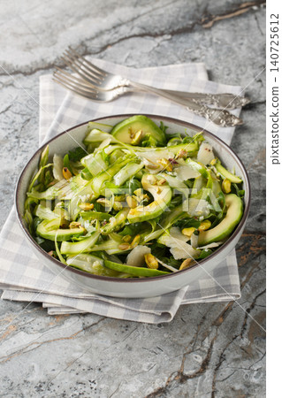 Fresh shaved asparagus salad with pistachios, parmesan cheese, avocado, arugula closeup in the plate. Vertical 140725612