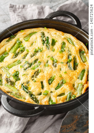 Savory baked frittata featuring asparagus and a fresh herb closeup in the skillet. Vertical 140725624