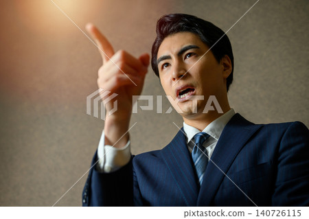 A businessman speaking enthusiastically while pointing his finger. A businessman speaking enthusiastically while pointing his finger. 140726115