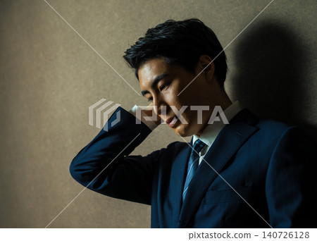 一個穿著西裝的男人,一手扶著頭,陷入沉思。 一個穿著西裝的男人,一手扶著頭,陷入沉思。 140726128