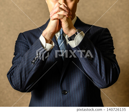 一位身穿西裝的商人雙手合十祈禱。 140726135