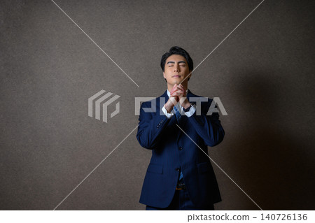 一位商人雙手合十，呈祈禱姿勢。 140726136