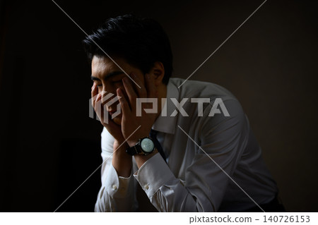 A businessman covers his face with a troubled expression. A businessman covers his face with a troubled expression. 140726153