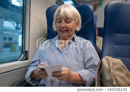 Happy senior woman using smartphone during train journey Happy senior woman using smartphone during train journey 140726239