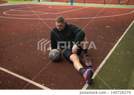 Smiling man sitting on basketball court and resting 140726270
