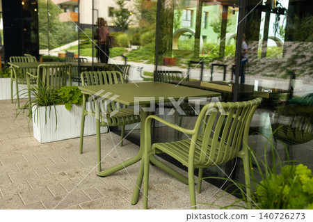 Modern green metal table and chairs on outdoor restaurant terrace 140726273