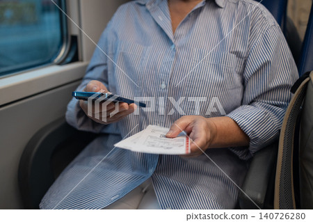 Close up of passenger holding train ticket and smartphone Close up of passenger holding train ticket and smartphone 140726280