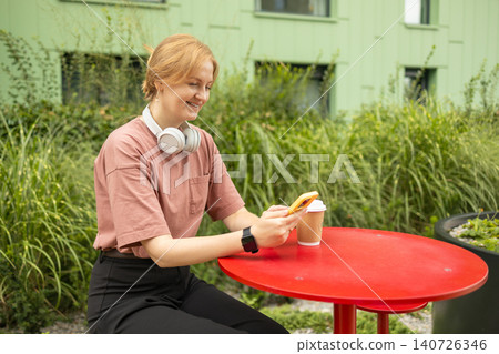 Smiling young woman using smartphone at outdoor terrace table Smiling young woman using smartphone at outdoor terrace table 140726346