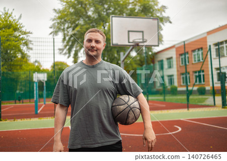 Portrait of young man holding basketball ball on court 140726465