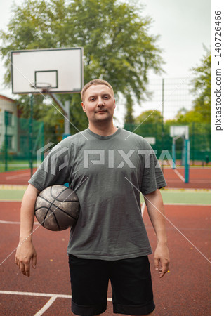Portrait of young man holding basketball ball on court Portrait of young man holding basketball ball on court 140726466