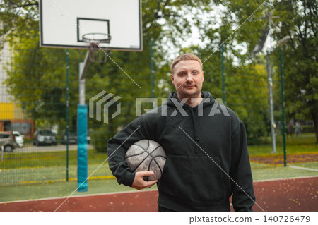 Portrait of smiling man holding basketball ball on court 140726479