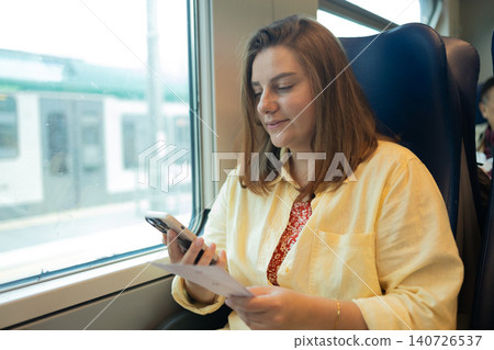 Young woman using smartphone while traveling by train Young woman using smartphone while traveling by train 140726537