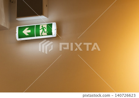 Green emergency exit sign indicating emergency wayfinding left Green emergency exit sign indicating emergency wayfinding left 140726623