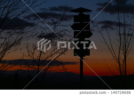 Signpost silhouette against sunset sky offering multiple directions 140726686