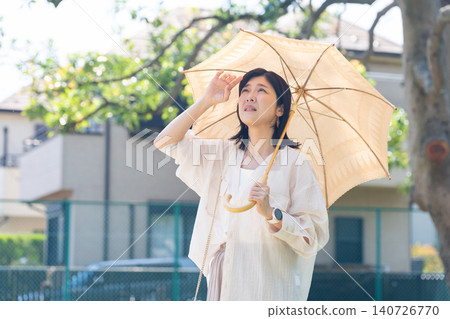 A woman who is feeling unwell is using a parasol. 140726770