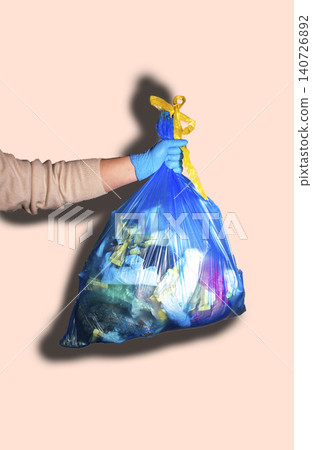 Hand holding full garbage bag on beige background isolated. Vertical high quality image Hand holding full garbage bag on beige background isolated. Vertical high quality image 140726892