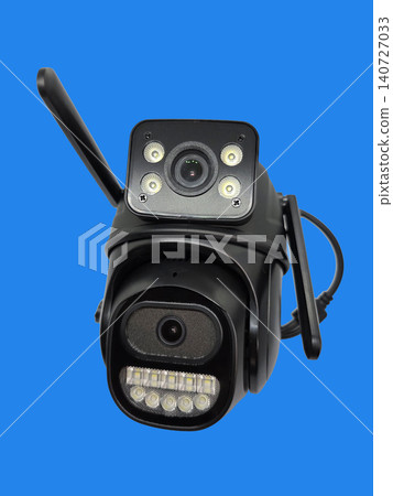 Black wireless security camera with dual lenses and LED lights isolated on blue background. Smart surveillance device for monitoring, safety and property protection. Black wireless security camera with dual lenses and LED lights isolated on blue background. Smart surveillance device for monitoring, safety and property protection. 140727033