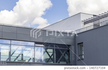 Modern commercial building facade with grey panels, glass windows, and blue sky reflection, Urban Modern commercial building facade with grey panels, glass windows, and blue sky reflection, Urban 140727104