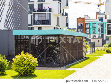 Modern covered bicycle parking storage shed in the courtyard of a residential building complex Modern covered bicycle parking storage shed in the courtyard of a residential building complex 140727322