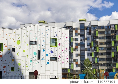 Modern kindergarten or school building with a playful colorful polka dot facade next to residential apartments Modern kindergarten or school building with a playful colorful polka dot facade next to residential apartments 140727404