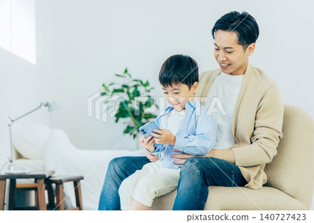 A young family looking at a smartphone in the living room 140727423