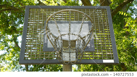 Street basketball hoop with chain net against green trees background Street basketball hoop with chain net against green trees background 140727553