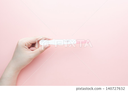 Pregnant woman holding a positive urine pregnancy test on pink background. Pregnancy test kit measure hCG levels in urine. Pregnant woman holding a positive urine pregnancy test on pink background. Pregnancy test kit measure hCG levels in urine. 140727632