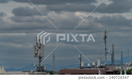 Communication antenna, base station, radio waves, communication infrastructure, mobile phone network, cloudy sky, cityscape Communication antenna, base station, radio waves, communication infrastructure, mobile phone network, cloudy sky, cityscape 140728347