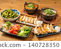A variety of à la carte dishes, dumplings, and hot pot dishes lined up on the table at the izakaya (Japanese pub) - a platter of banquet menu items. 140728350