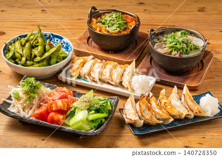 A variety of à la carte dishes, dumplings, and hot pot dishes lined up on the table at the izakaya (Japanese pub) - a platter of banquet menu items. 140728350