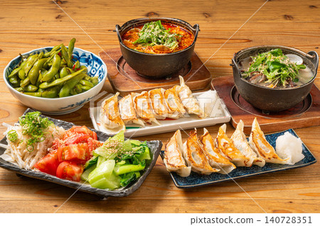 A variety of à la carte dishes, dumplings, and hot pot dishes lined up on the table at the izakaya (Japanese pub) - a platter of banquet menu items. 140728351