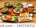 A variety of à la carte dishes, dumplings, and hot pot dishes lined up on the table at the izakaya (Japanese pub) - a platter of banquet menu items. 140728352