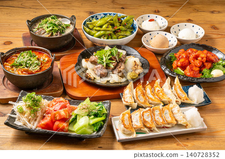A variety of à la carte dishes, dumplings, and hot pot dishes lined up on the table at the izakaya (Japanese pub) - a platter of banquet menu items. 140728352