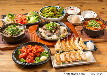 A variety of à la carte dishes, dumplings, and hot pot dishes lined up on the table at the izakaya (Japanese pub) - a platter of banquet menu items. 140728353