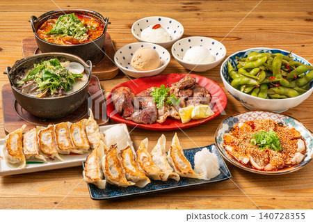 A variety of à la carte dishes, dumplings, and hot pot dishes lined up on the table at the izakaya (Japanese pub) - a platter of banquet menu items. 140728355