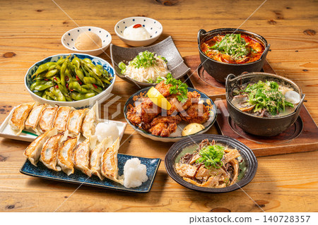 A variety of à la carte dishes, dumplings, and hot pot dishes lined up on the table at the izakaya (Japanese pub) - a platter of banquet menu items. 140728357