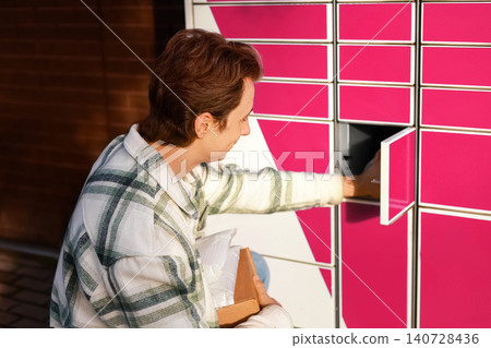 A man uses a contactless parcel locker for package pickup. This automated delivery service and logistics technology makes ecommerce shopping fast and easy. A man uses a contactless parcel locker for package pickup. This automated delivery service and logistics technology makes ecommerce shopping fast and easy. 140728436