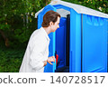 Man holding stomach in pain opening a blue outdoor portable toilet. Concept of an urgent toilet emergency, diarrhea, and digestive discomfort. 140728517