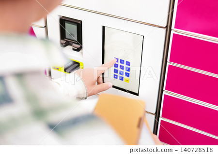 Close up of a hand entering a pin code on a parcel locker touchscreen terminal. Concept of e-commerce online shopping delivery service and package pickup. Close up of a hand entering a pin code on a parcel locker touchscreen terminal. Concept of e-commerce online shopping delivery service and package pickup. 140728518