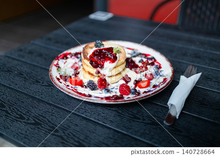 Stack of cottage cheese pancakes syrniki with berry sauce and mint close up Stack of cottage cheese pancakes syrniki with berry sauce and mint close up 140728664