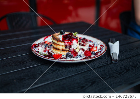 Stack of cottage cheese pancakes syrniki with berry sauce and mint close up Stack of cottage cheese pancakes syrniki with berry sauce and mint close up 140728675